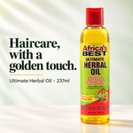 A bottle of Africa's Best Ultimate Herbal Oil stands on a white surface against a softly lit white background with decorative leaf shadows. Large text on the left reads, 'Haircare, with a golden touch.