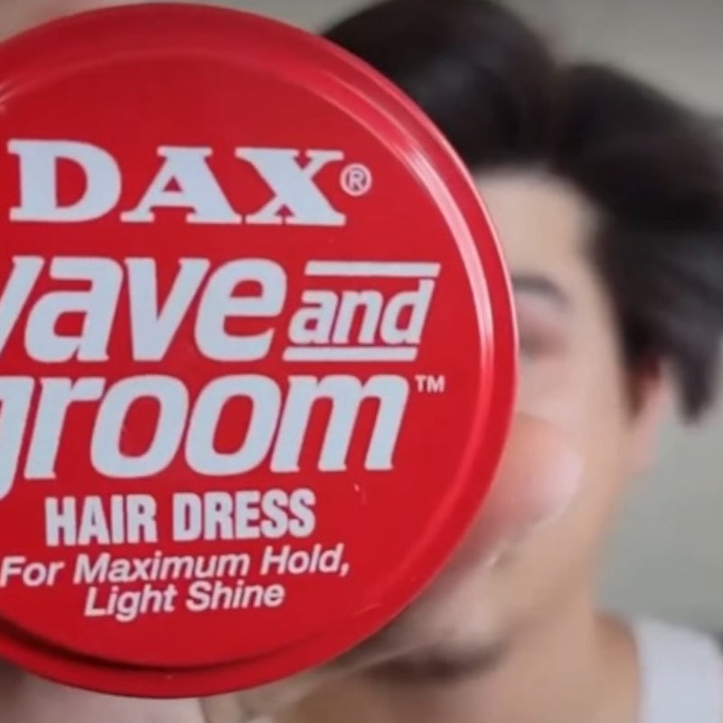 Red container of DAX Wave and Groom hair dress with a blurred person in the background