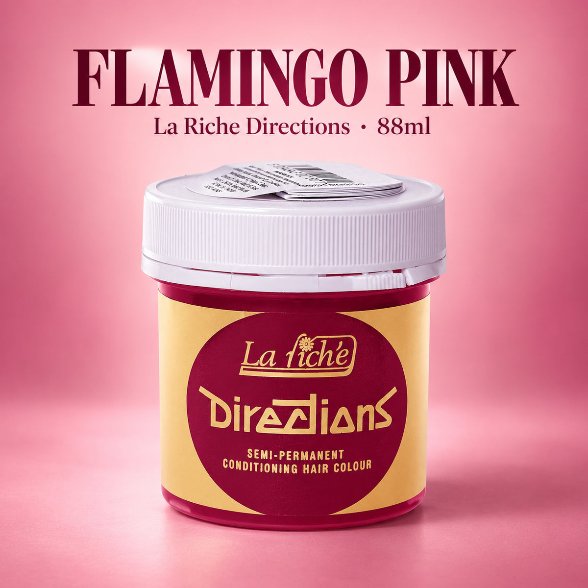 A jar of La Riche Directions hair color in 'Flamingo Pink' against a pink gradient background. The product container has a yellow and maroon label with a white lid, and the text 'FLAMINGO PINK' is written at the top.